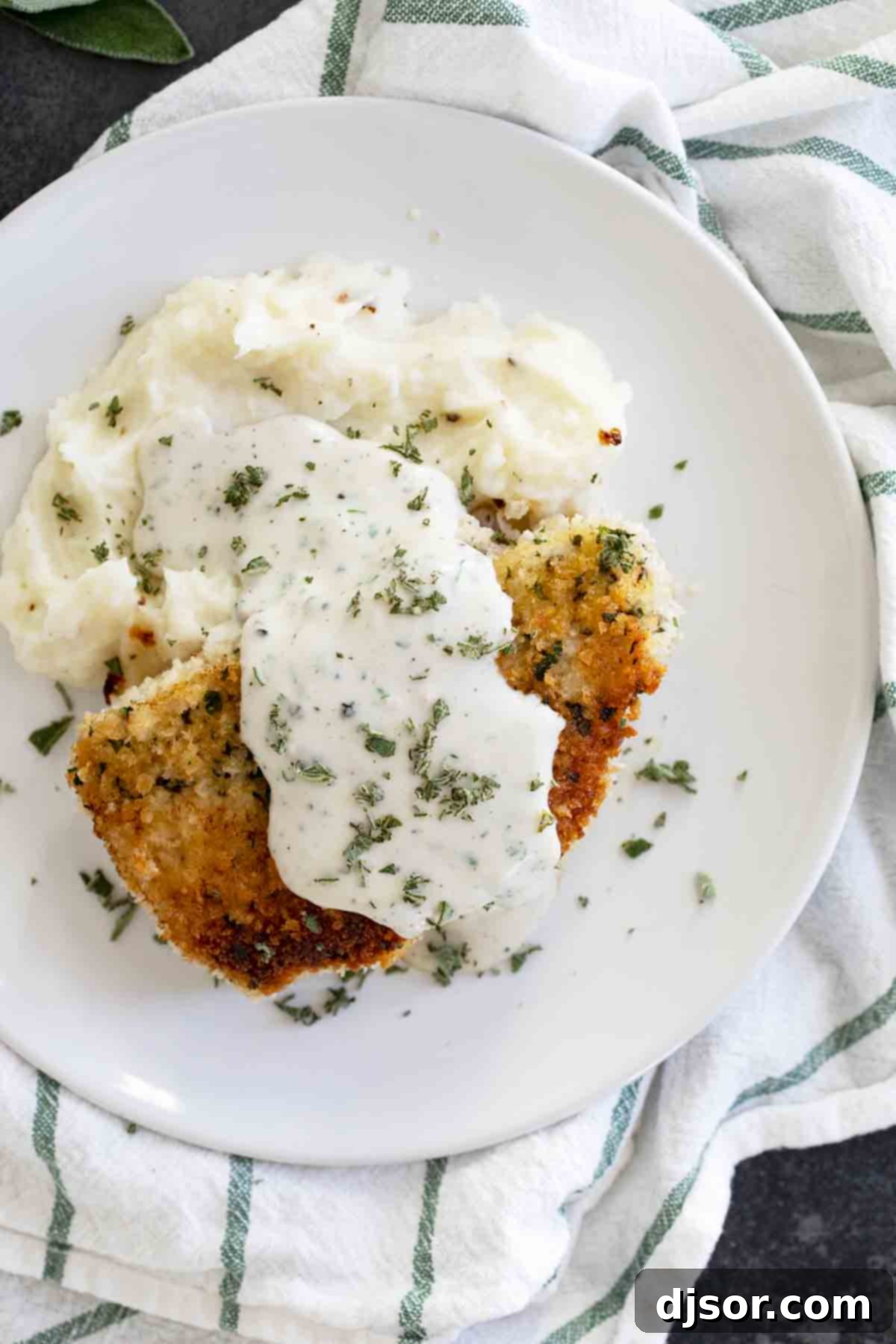 Breaded pork chops with creamy herb gravy served over mashed potatoes.