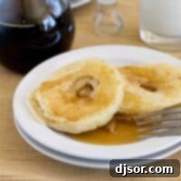 Apple Ring Pancakes 2 Apple Pancake Rings on a plate served with syrup and fresh apple slices.