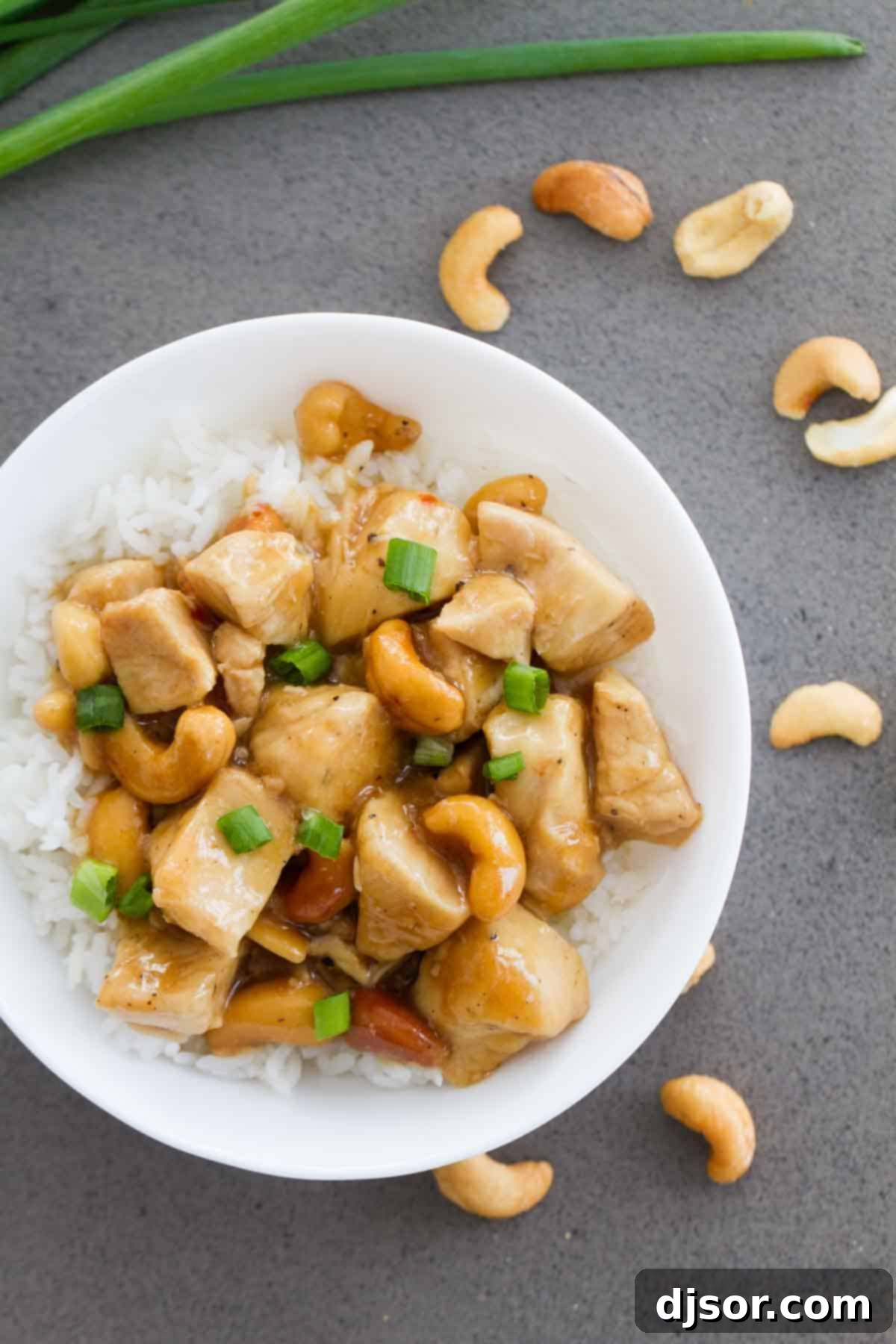 Bowl of Cashew Chicken over Rice with cashews on the table