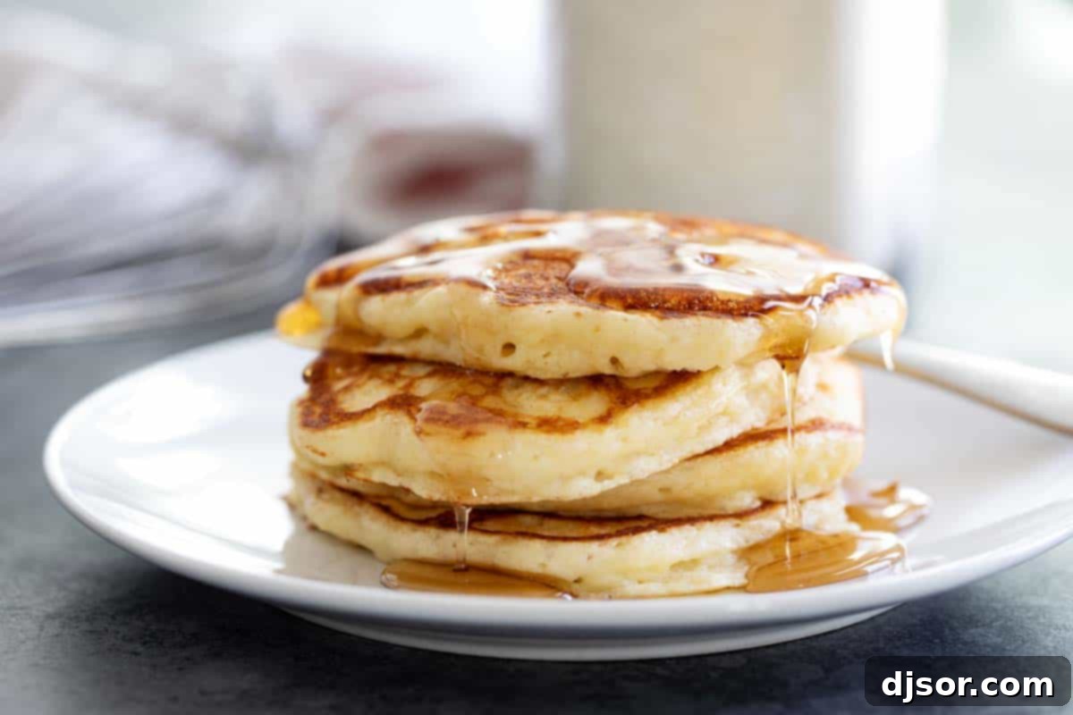 Enjoying Your Fluffy Homemade Pancakes with Syrup Stack of fluffy pancakes drizzled with syrup, on a white plate