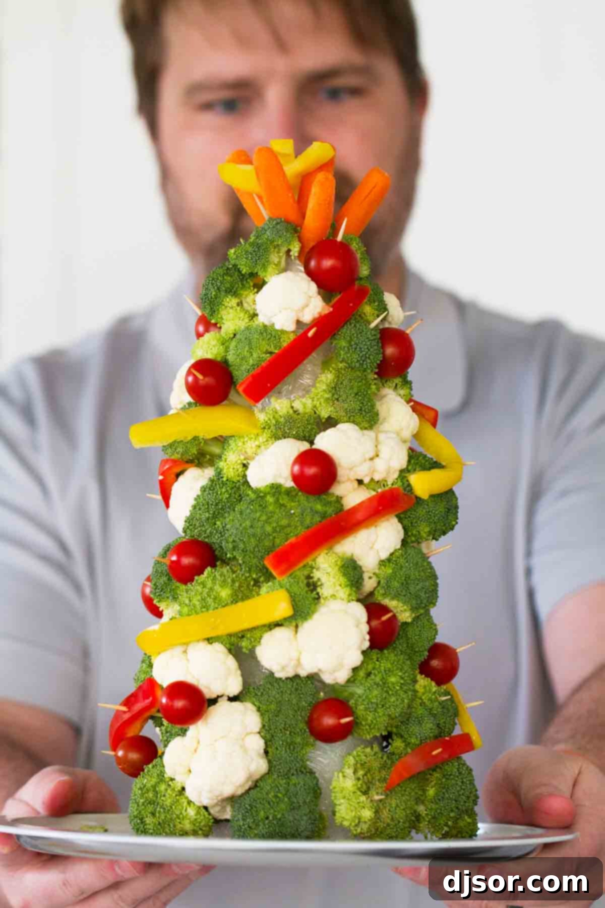 Festive Veggie Trees with Savory Bacon Chive Ranch Dip 6 A proud man holding a completed Christmas tree made from fresh vegetables, ready to be enjoyed.