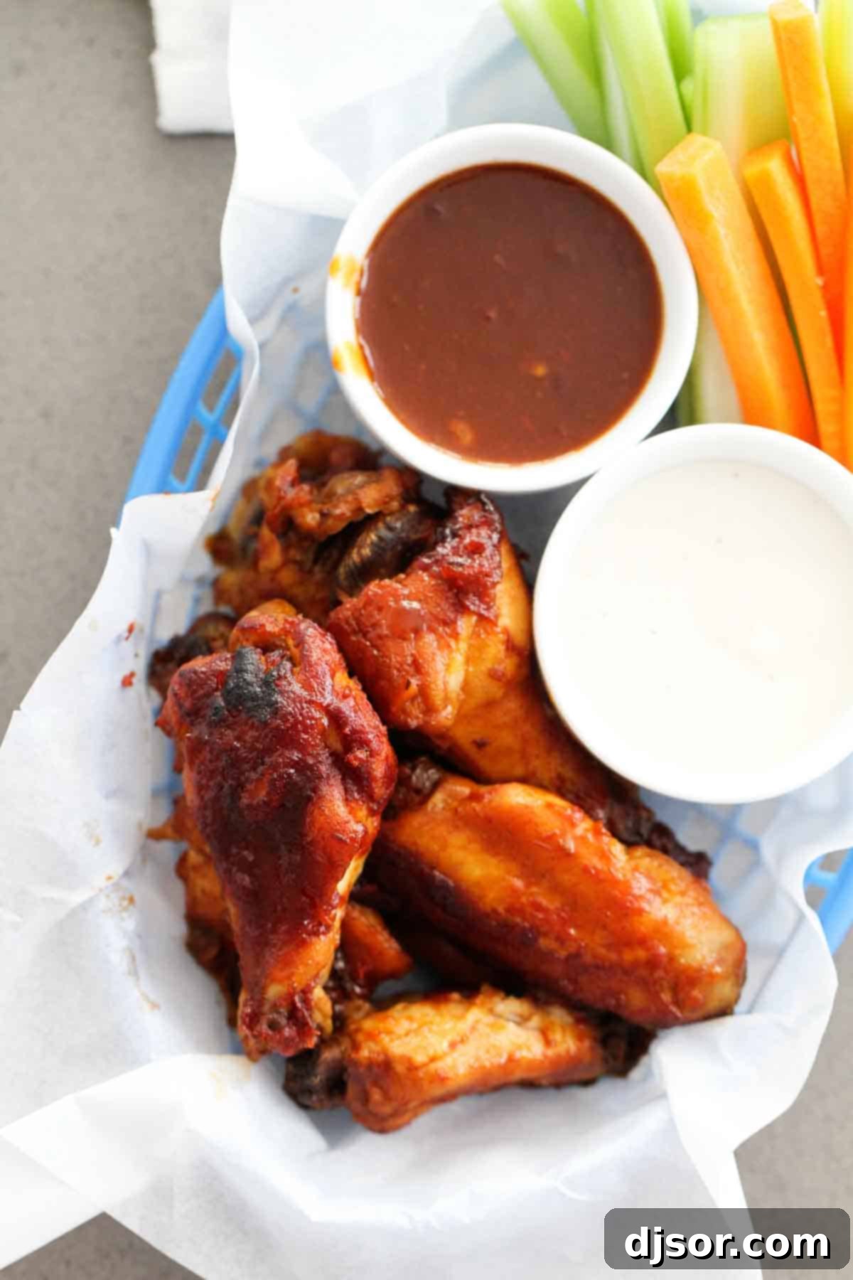 Crockpot Chicken Wings with barbecue sauce in a basket with dipping sauces.