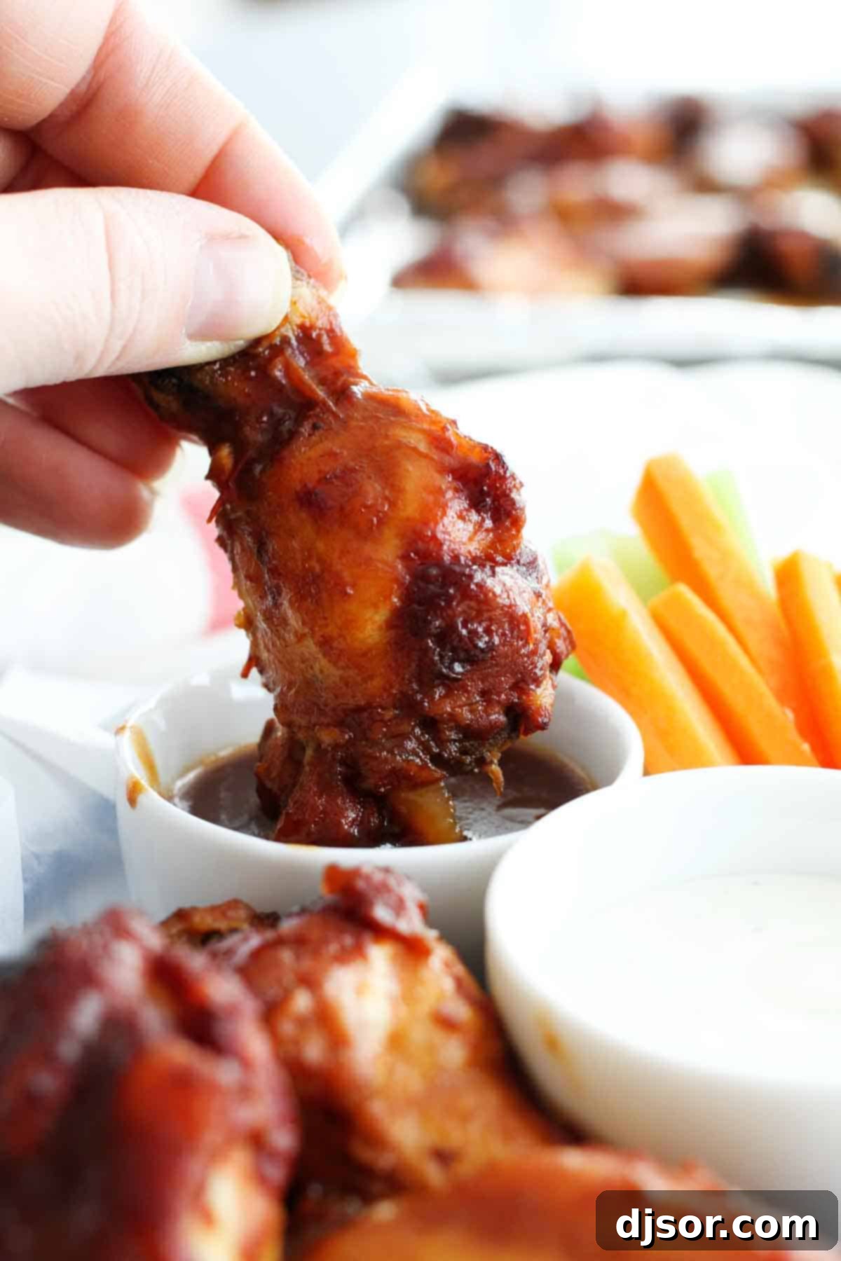 Dipping Crockpot Chicken Wings with Barbecue Sauce into sauce.
