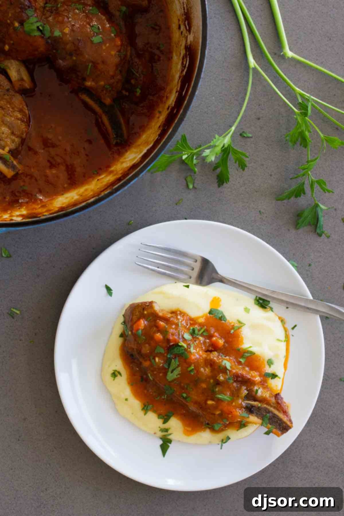 Braised Country Style Ribs served elegantly over creamy polenta on a white plate, ready to be enjoyed.