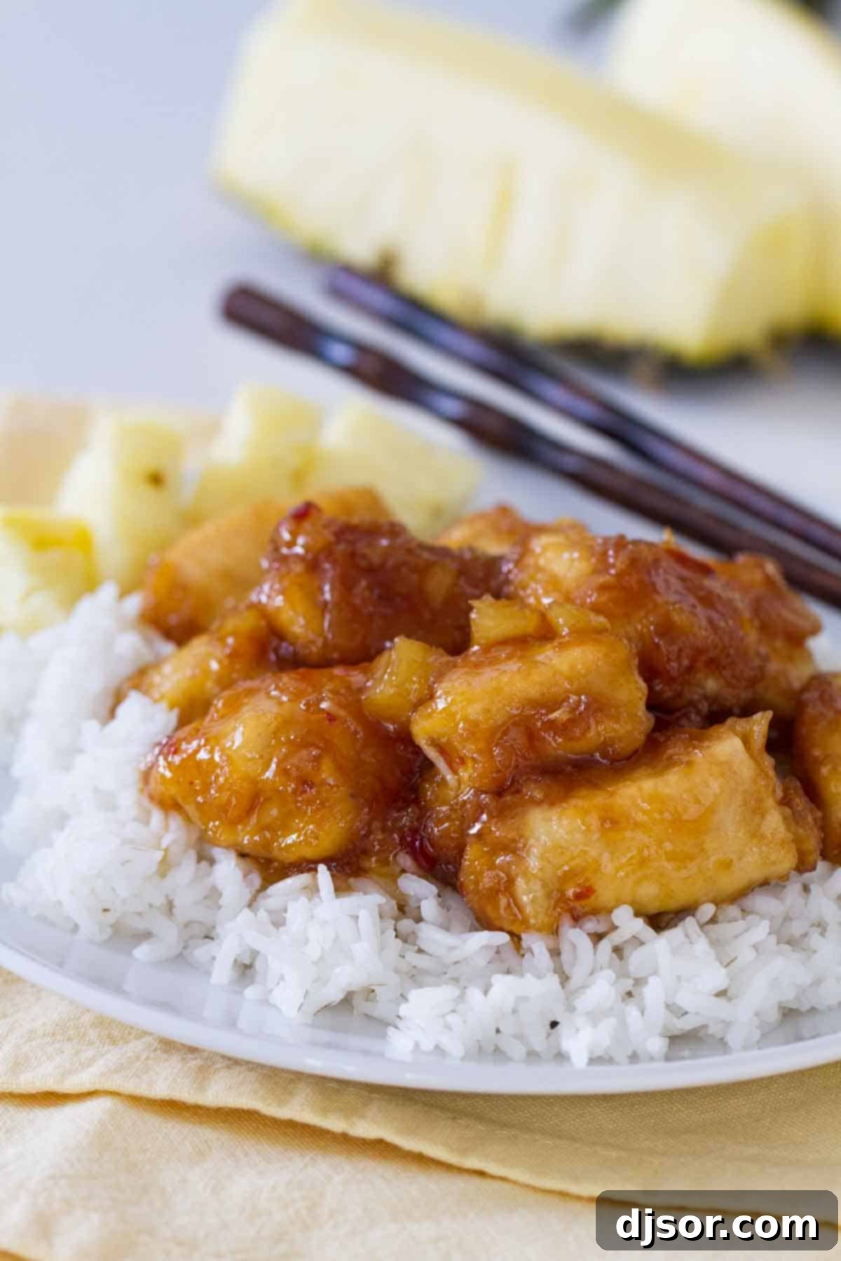 Make it a Make-Your-Own-Take-Out night with this sweet and savory Pineapple Chicken. Crispy chicken is cooked in a sweet pineapple sauce. Serve over rice for a dinner that is sure to be a hit! pineapple chicken over rice on a plate