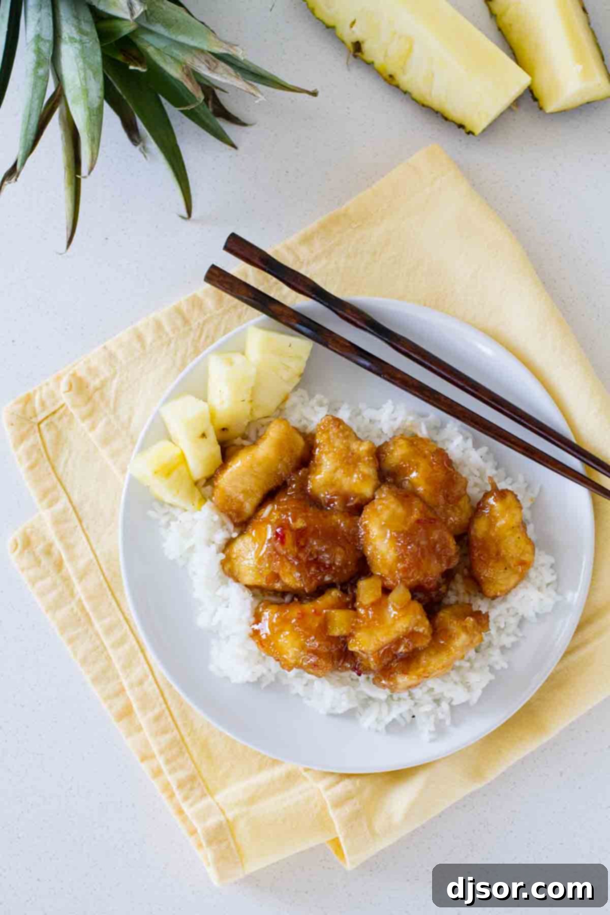 Make it a Make-Your-Own-Take-Out night with this sweet and savory Pineapple Chicken. Crispy chicken is cooked in a sweet pineapple sauce. Serve over rice for a dinner that is sure to be a hit! overhead view of pineapple chicken over rice