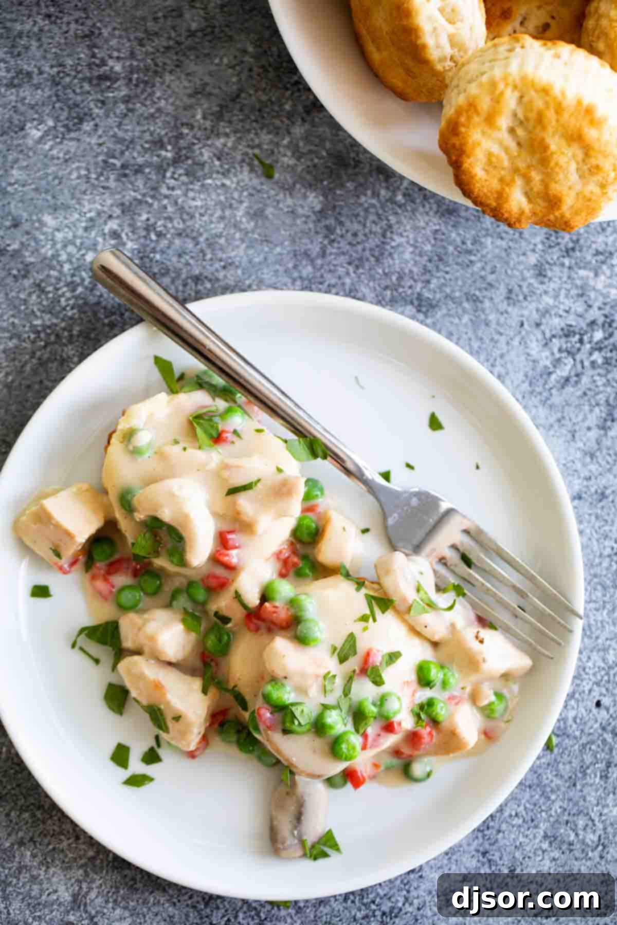 Classic Chicken a la King on Biscuits Overhead shot of two fluffy biscuits generously topped with creamy Chicken a la King gravy and fresh parsley.