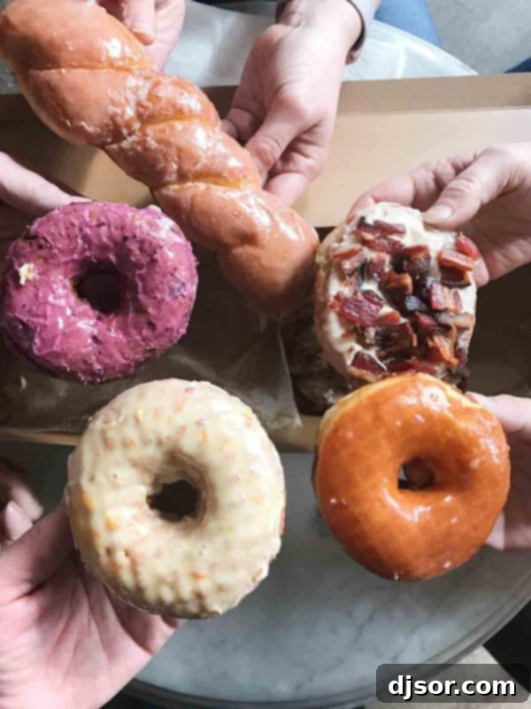 A diverse collection of Sidecar Doughnuts, fresh from the fryer, featuring popular and seasonal flavors. An inviting display of assorted gourmet doughnuts from Sidecar Doughnuts, showcasing various glazes and toppings, including cake and yeast varieties.