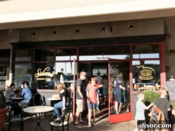 The welcoming facade of Sidecar Doughnuts, beckoning doughnut lovers. A closer look at the inviting entrance and outdoor seating area of Sidecar Doughnuts, capturing its charming roadside appeal.