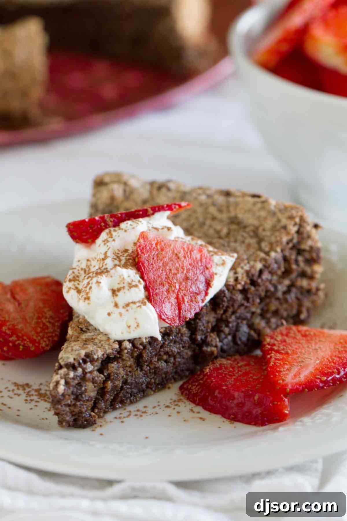 Exquisite Italian Chocolate Almond Flourless Cake A perfectly sliced Italian Chocolate Almond Flourless Cake, topped generously with whipped cream and vibrant strawberries, ready to be enjoyed.