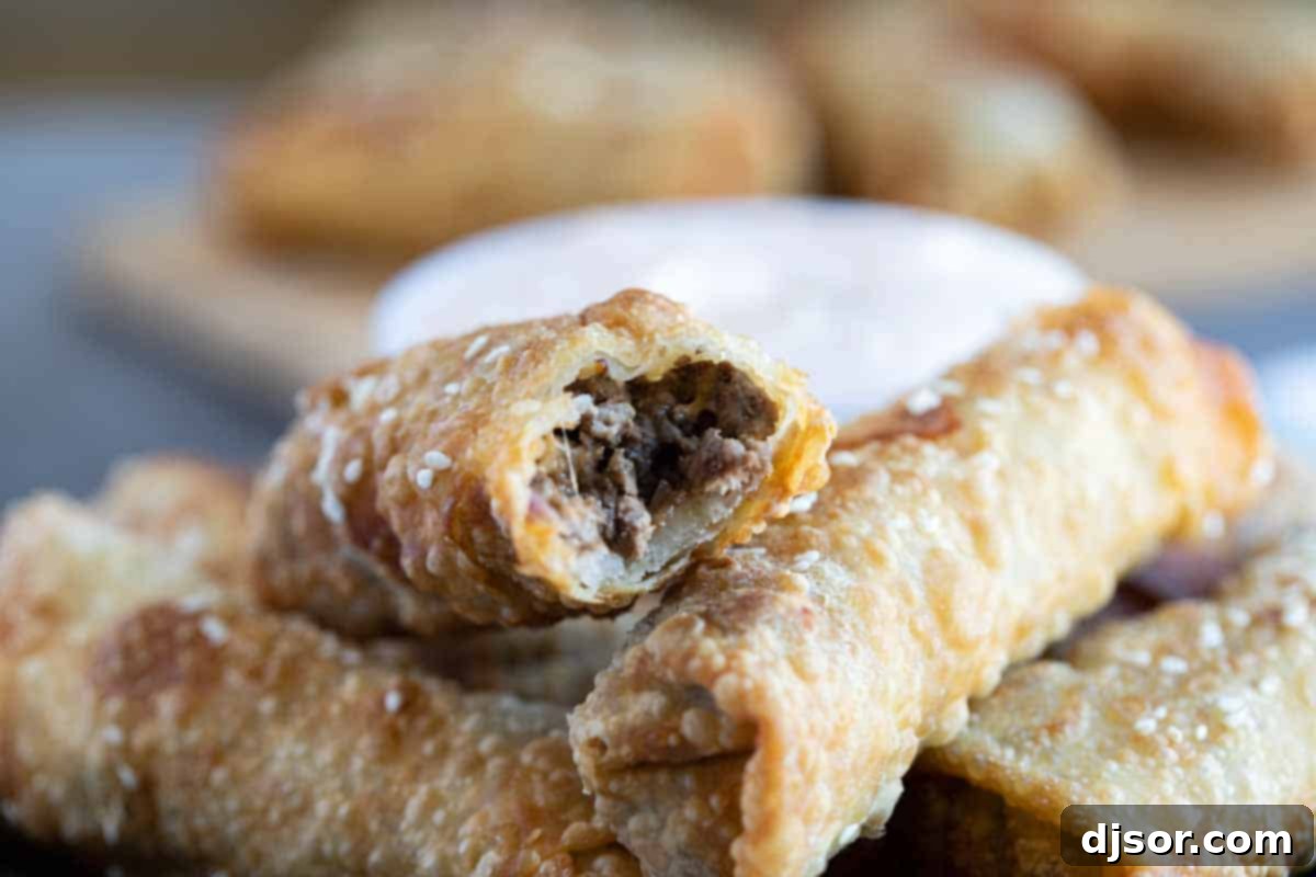 Cheeseburger Crunch Rolls 10 Close-up of a cheeseburger eggroll with a bite taken out, revealing the savory beef and melted cheddar cheese filling inside, proving its deliciousness.
