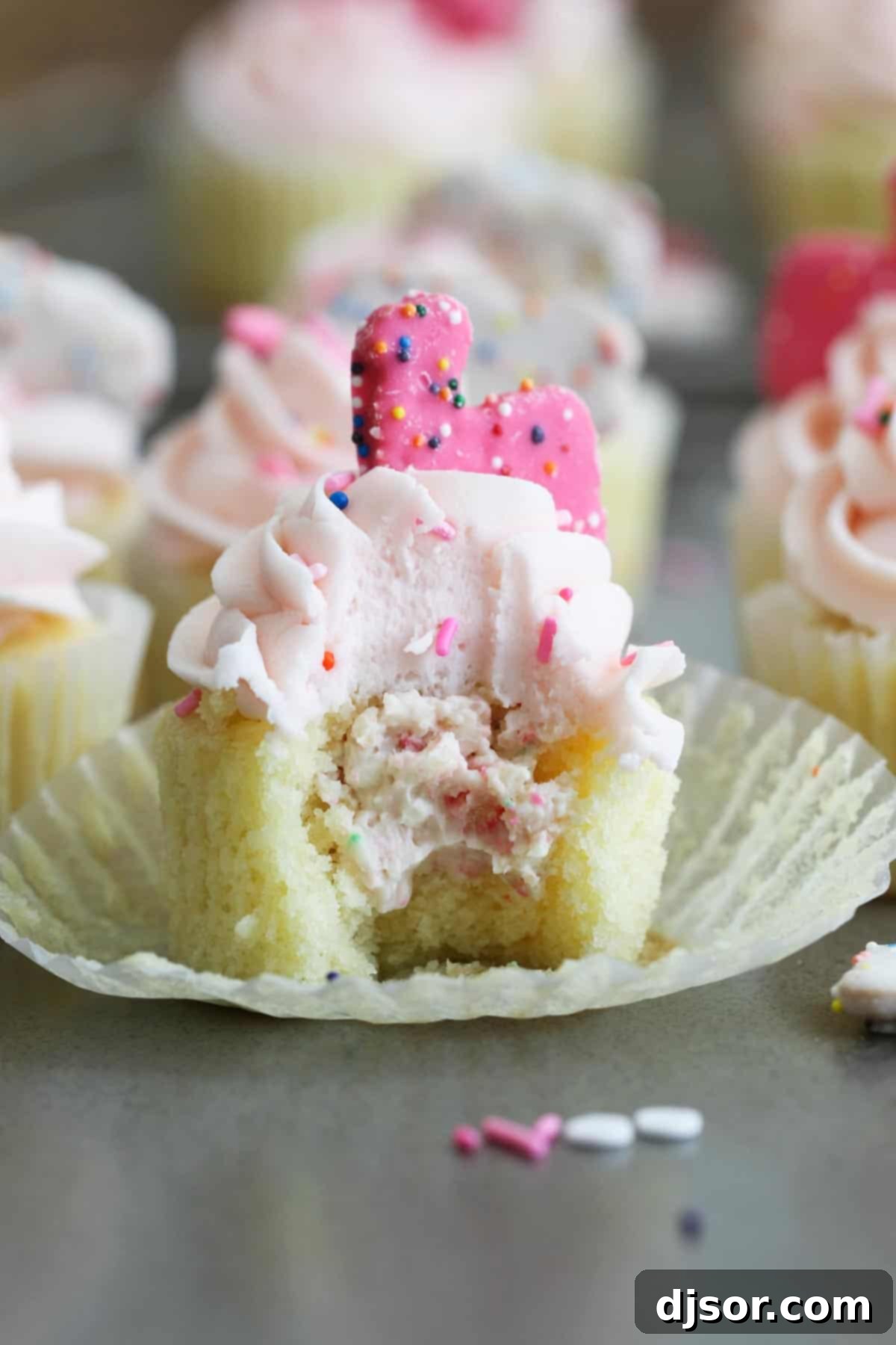Inside view of a Circus Animal Cookie Cupcake revealing the cheesecake center. A Circus Animal Cookie Cupcake with a bite taken, showcasing its delicious filling.