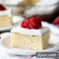 slice of Homemade Tres Leches Cake topped with a fresh strawberry