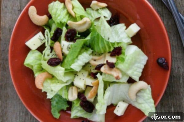 Crafting Your Perfect Thanksgiving 6 A festive Winter Salad in a large bowl, featuring crisp greens, sliced pears, apples, dried cranberries, and cashews, tossed in a bright lemon poppy seed dressing.