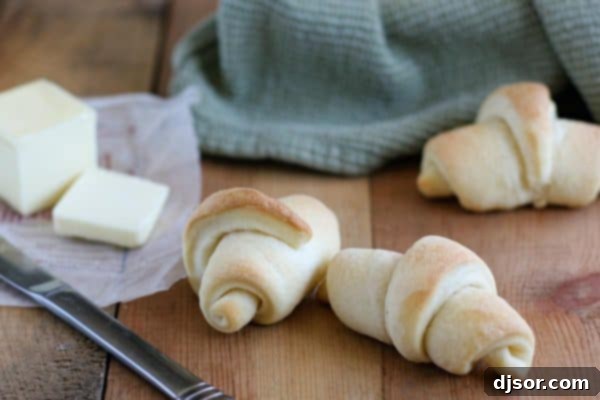 Crafting Your Perfect Thanksgiving 8 Fluffy, golden-brown Butterhorns served with pats of butter, arranged on a rustic wooden board.