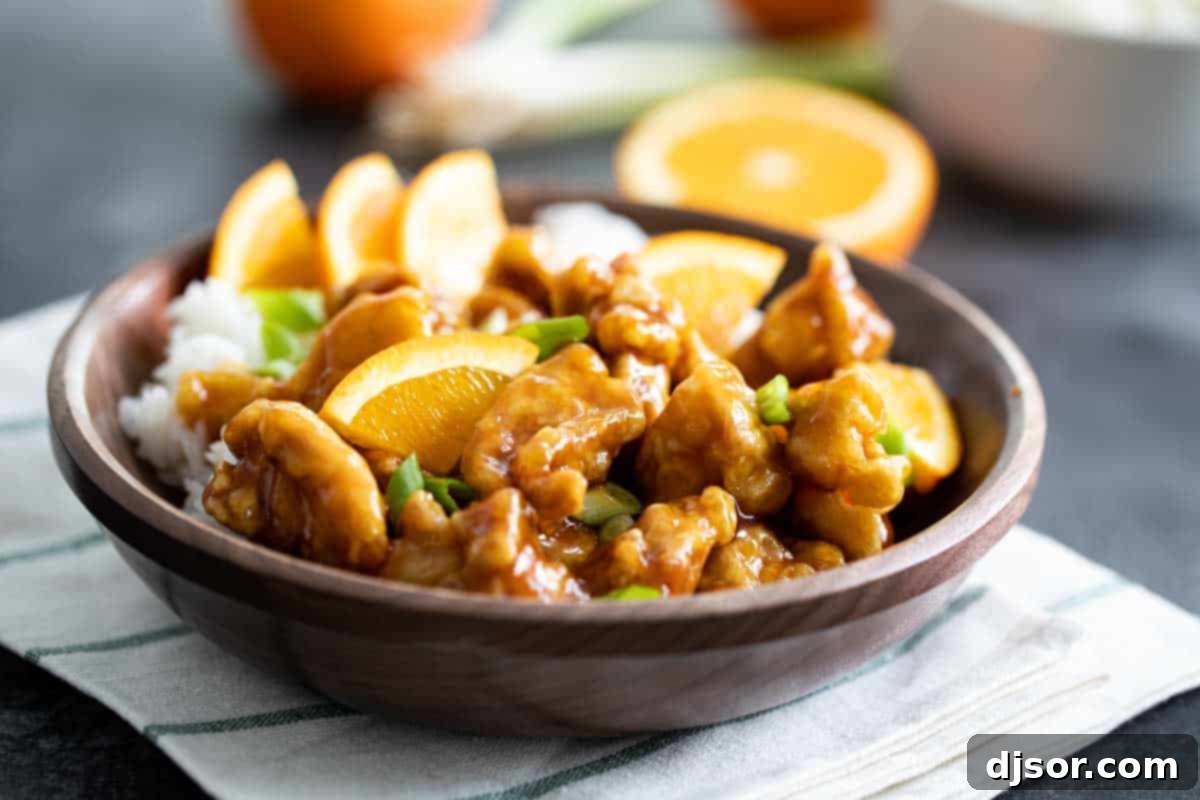 Experience the Best Homemade Orange Chicken Recipe – Crispy, Sweet, and Tangy! A vibrant bowl of crispy orange chicken served over fluffy white rice, garnished with fresh green onions.
