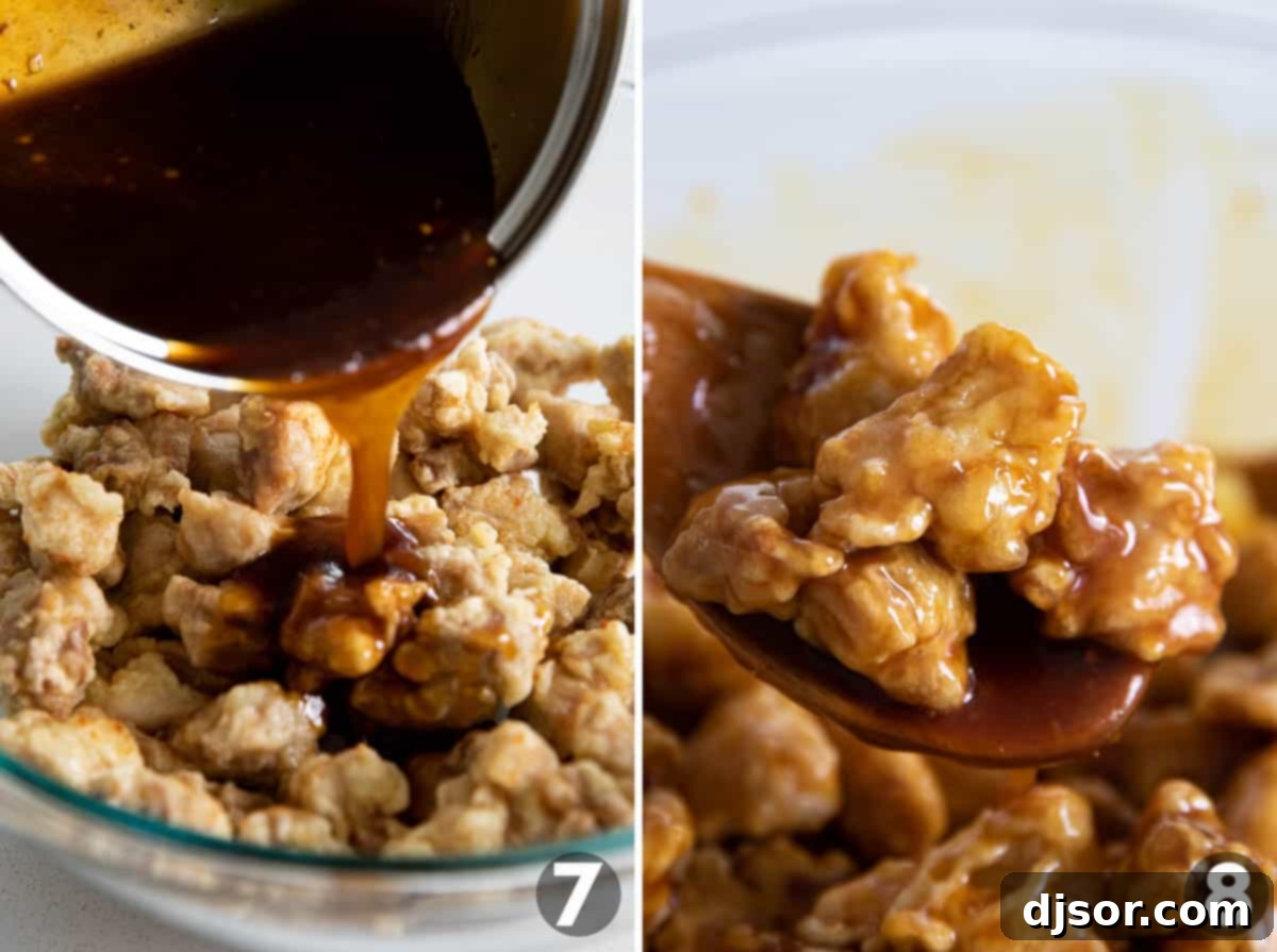 A large bowl of golden, crispy orange chicken is being generously coated with the thick, glossy, sweet, and savory orange sauce.