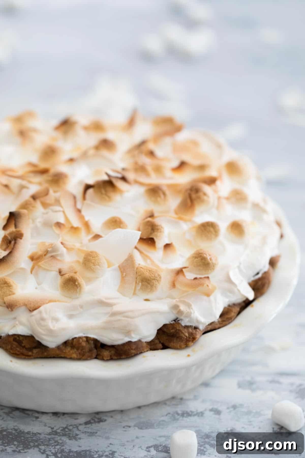 Take your pie game up a step with this Sweet Potato Pie with Marshmallow Coconut Meringue. A rich, smooth sweet potato pie is topped with a tall marshmallow meringue. A bit of coconut tops off this show stopping pie recipe. A complete Sweet Potato Pie adorned with a towering, golden-brown marshmallow coconut meringue, baked to perfection.