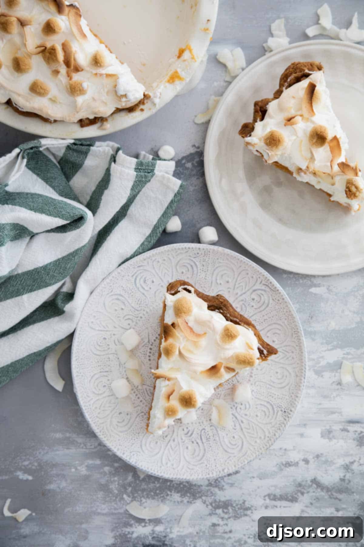 Take your pie game up a step with this Sweet Potato Pie with Marshmallow Coconut Meringue. A rich, smooth sweet potato pie is topped with a tall marshmallow meringue. A bit of coconut tops off this show stopping pie recipe. Four generous slices of Sweet Potato Pie with a tall marshmallow coconut meringue are presented on a white serving dish, ready for sharing.
