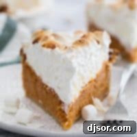 Toasted Coconut Marshmallow Meringue Sweet Potato Pie 2 A beautifully sliced Sweet Potato Pie with a tall, golden marshmallow coconut meringue, served on a plate with a fork, ready to be enjoyed.