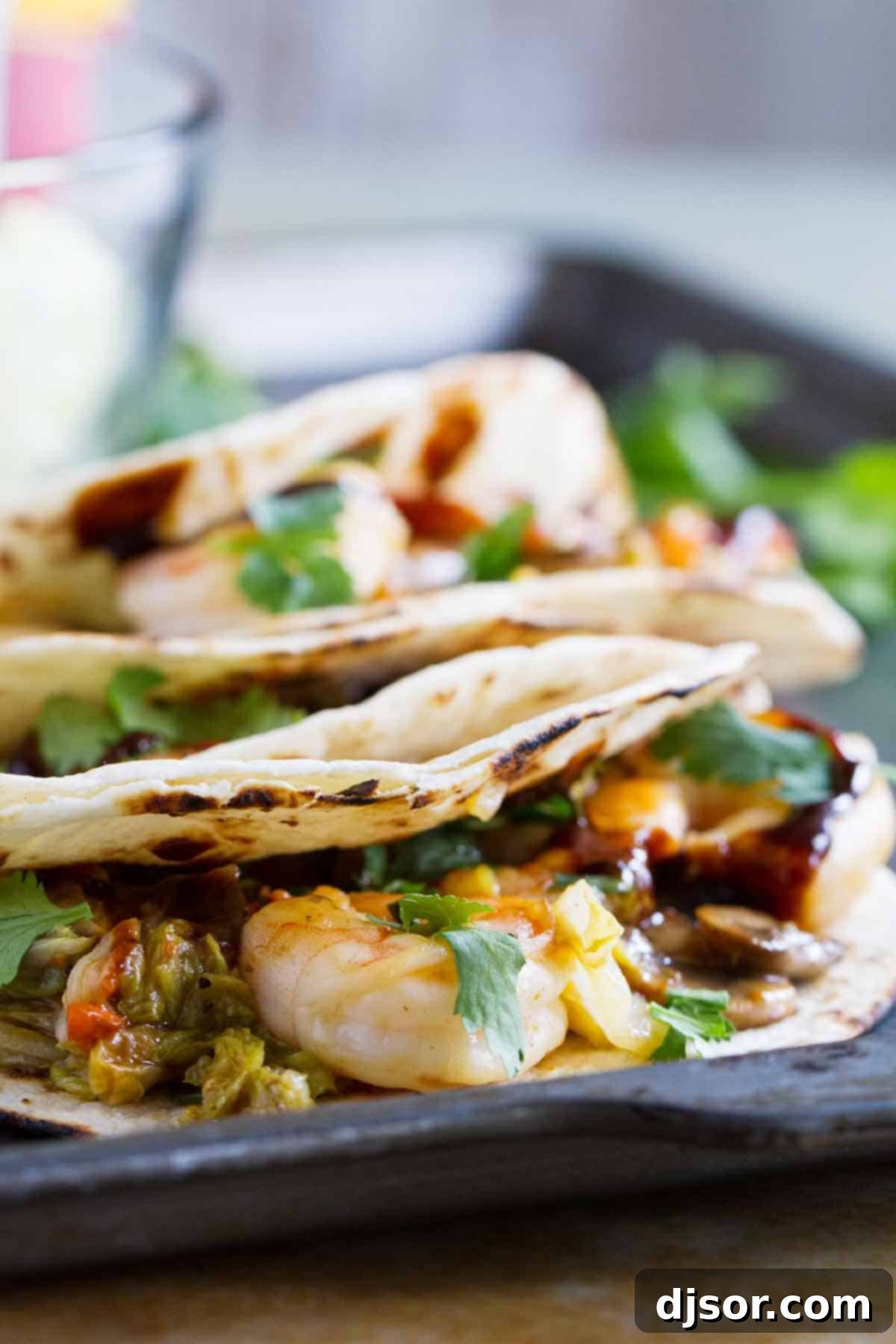 Moo Shu Shrimp served in warm tortillas, garnished with cilantro and hoisin sauce.
