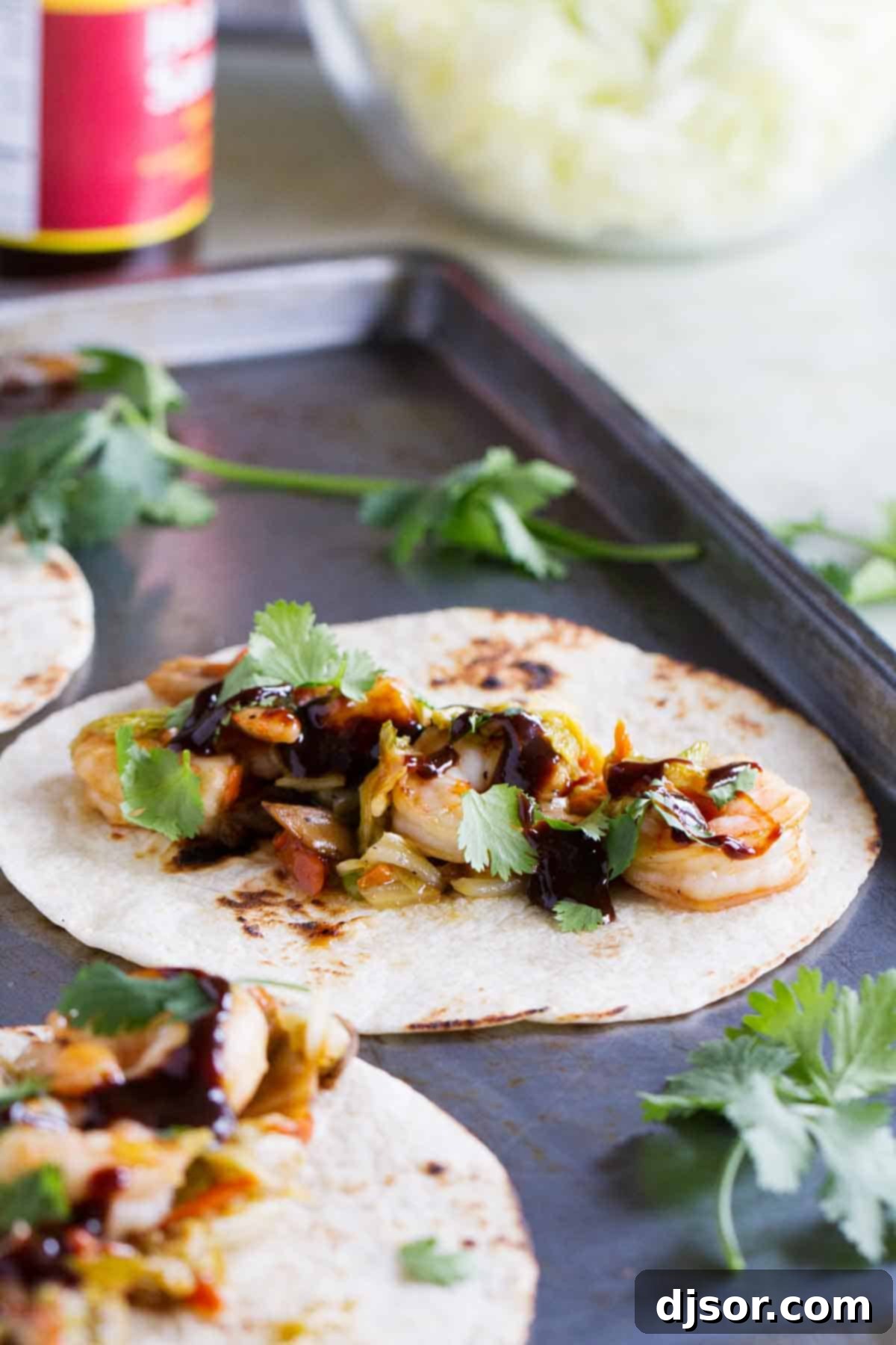 Prepared Moo Shu Shrimp mixture in tortillas, generously topped with hoisin sauce and fresh cilantro.