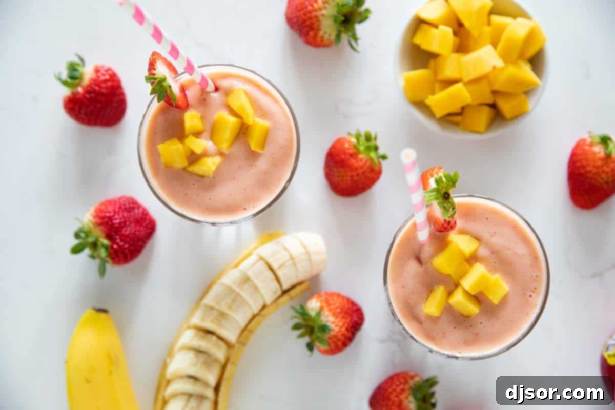overhead view of tropical smoothie with fruit around the cups