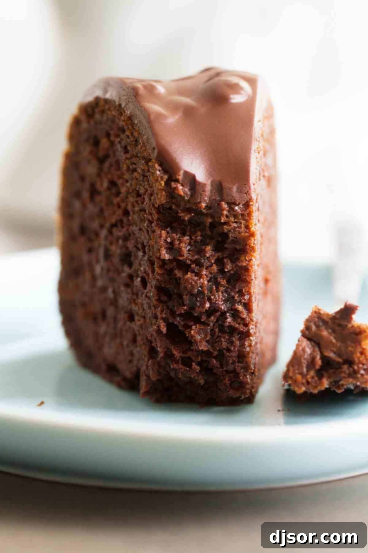 Moist Chocolate Bundt Cake Texture A slice of chocolate bundt cake with chocolate glaze, a fork having taken a bite, revealing the moist and tender cake texture.
