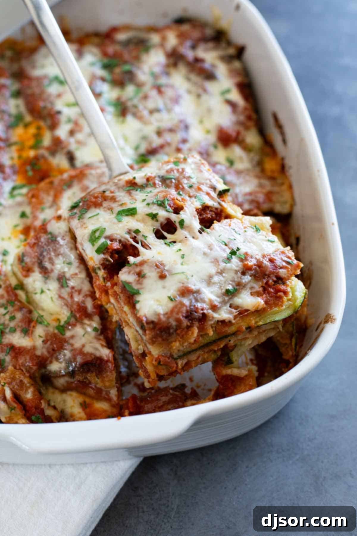 Baked Zucchini Parmesan 7 A spatula lifting a generous, perfectly portioned slice of Zucchini Parmesan from a casserole dish onto a serving plate, revealing its warm, layered interior.