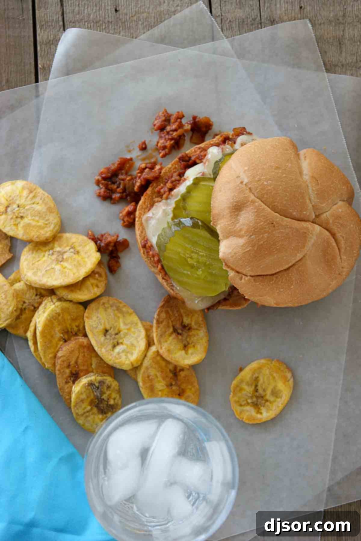 Mojo Sloppy Joes 4 Close-up of a Cuban Sloppy Joe sandwich, showing the generous filling of pork and chorizo, melted Swiss cheese, and topped with crisp pickle slices on a toasted bun.