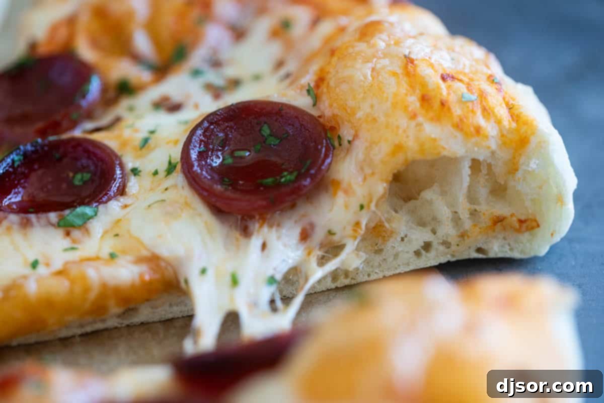 Slice of pizza made with artisan pizza dough showing interior texture of dough.