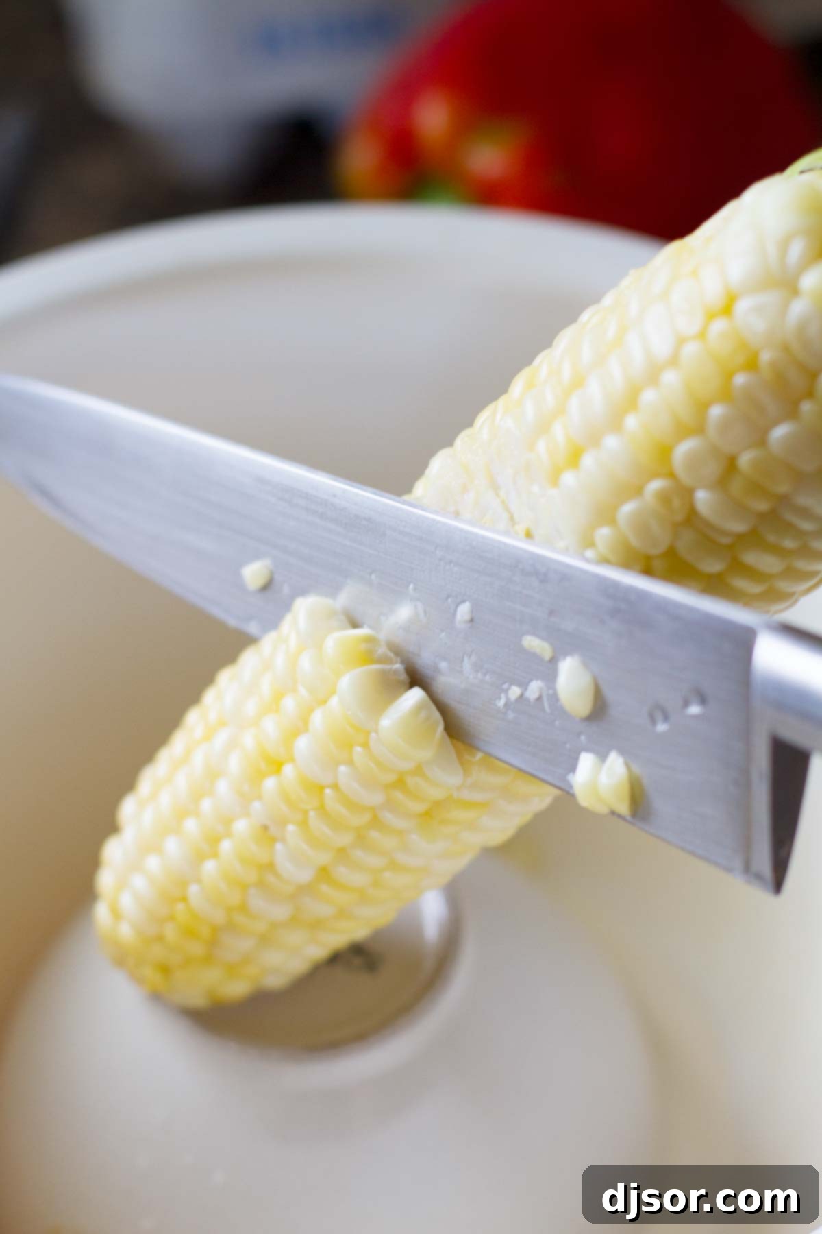Closeup of fresh corn being skillfully cut from the cob into a mixing bowl, illustrating the process to capture flavorful corn milk
