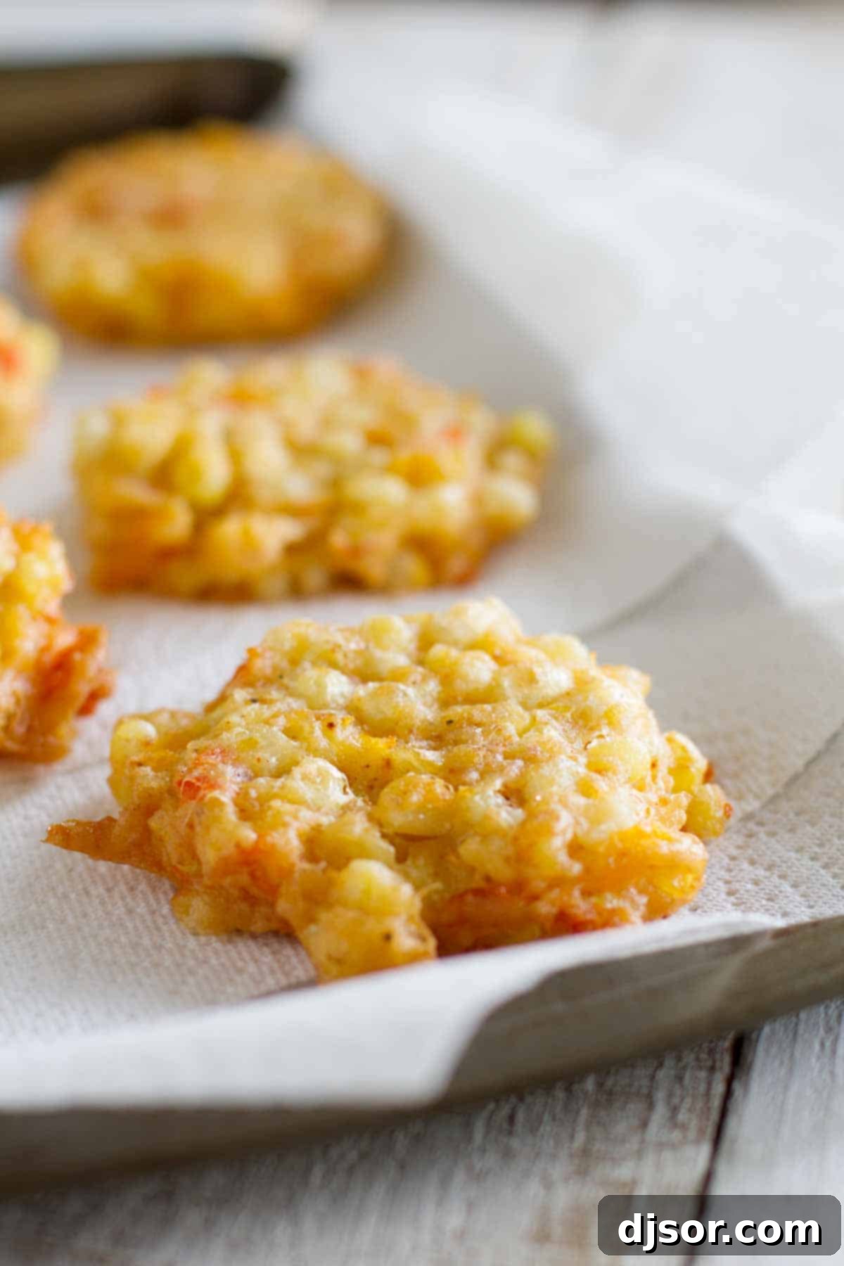 Close-up of golden-brown Corn Fritters, freshly cooked and draining on paper towels, showcasing their crispy texture
