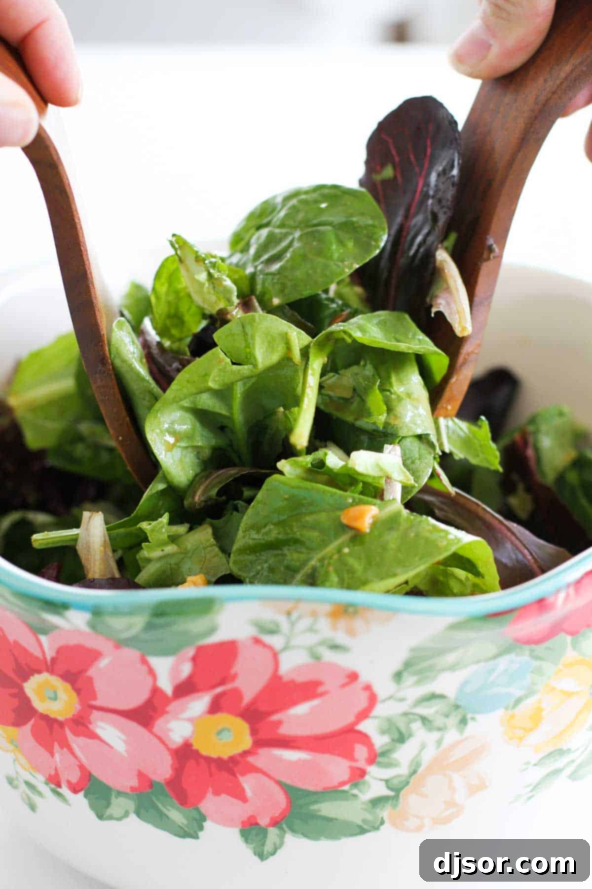 Tossing Thai Beef Salad: A Medley of Freshness A close-up shot of a Thai Beef Salad being tossed with wooden salad tongs, highlighting the fresh ingredients and dressing.