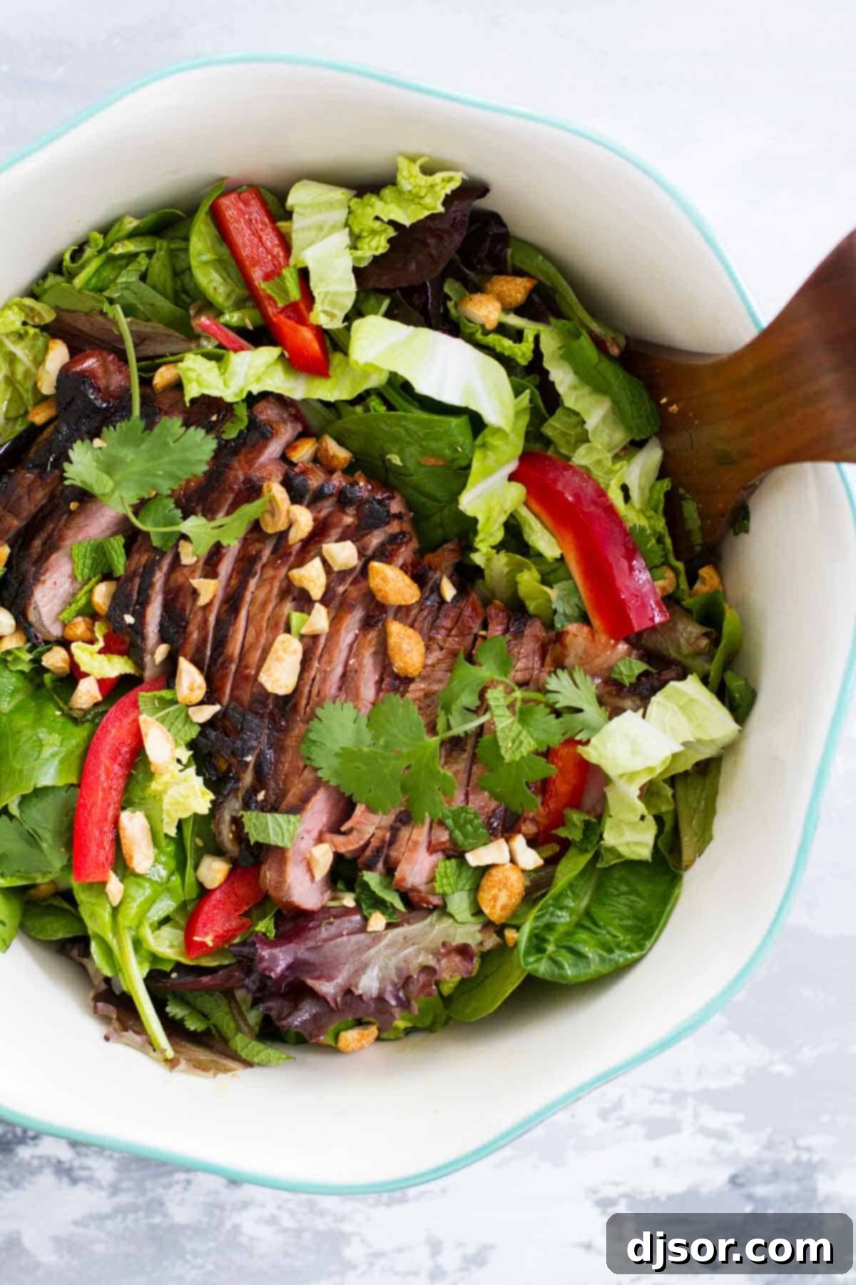Thai Beef Salad: A Colorful & Flavorful Feast A large salad bowl filled with Thai Beef Salad, showcasing the colorful medley of vegetables, sliced steak, and peanuts.