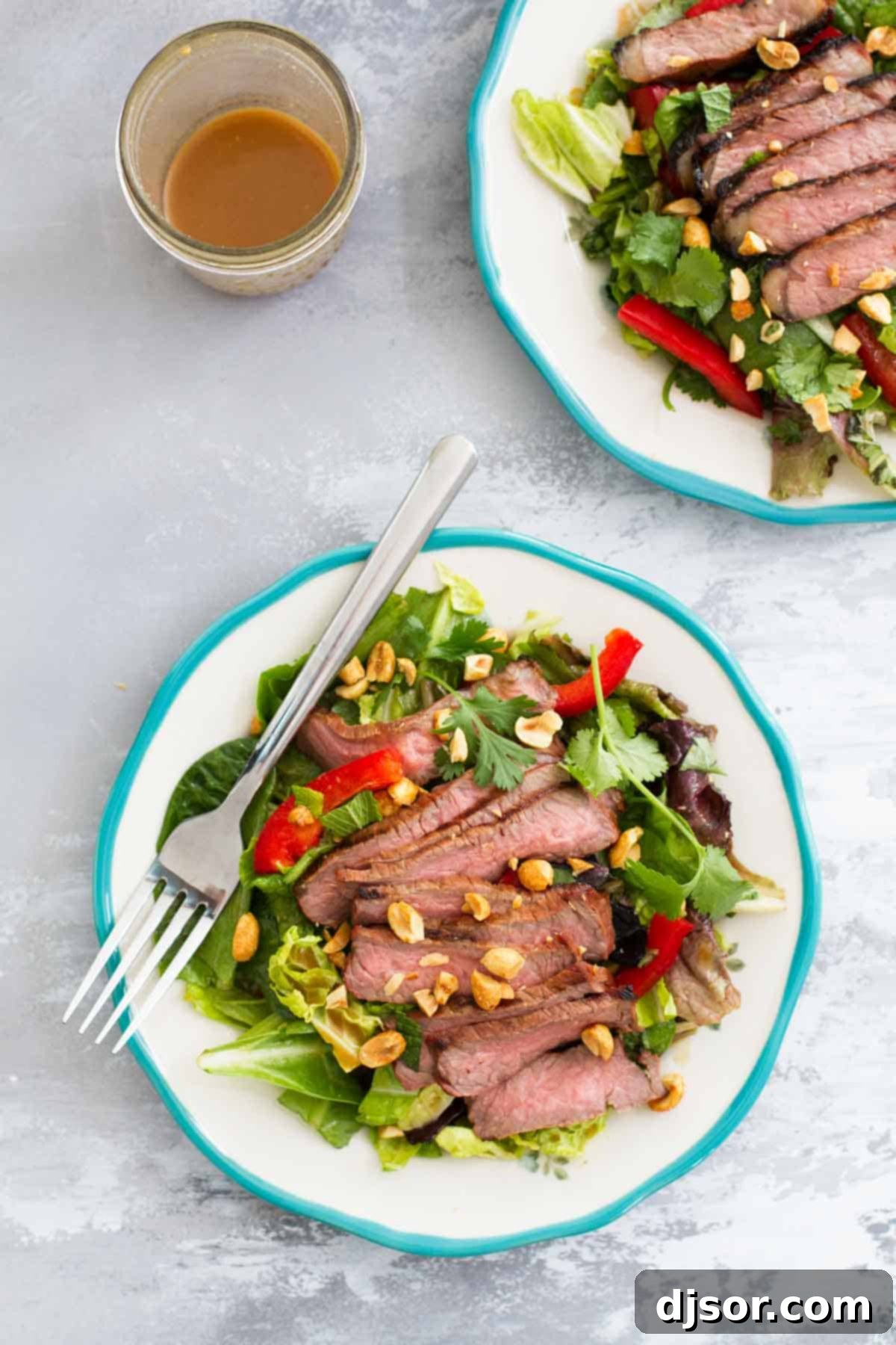 Thai Beef Salad: A Perfect Balance of Flavor Two plates of Thai Beef Salad, artfully arranged with sliced steak, colorful vegetables, and a side of creamy peanut dressing.