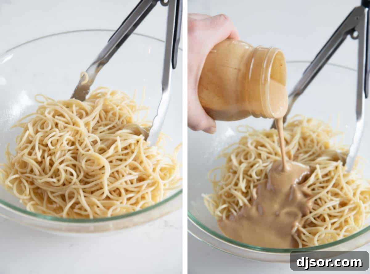 Rich, homemade peanut sauce being generously poured over a bed of perfectly cooked spaghetti noodles in a large mixing bowl.
