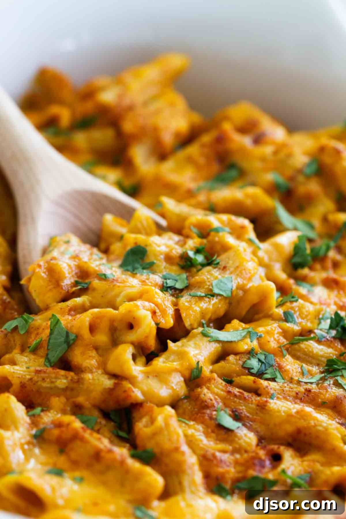 Dish of pumpkin cheddar mac and cheese with a wooden spoon.