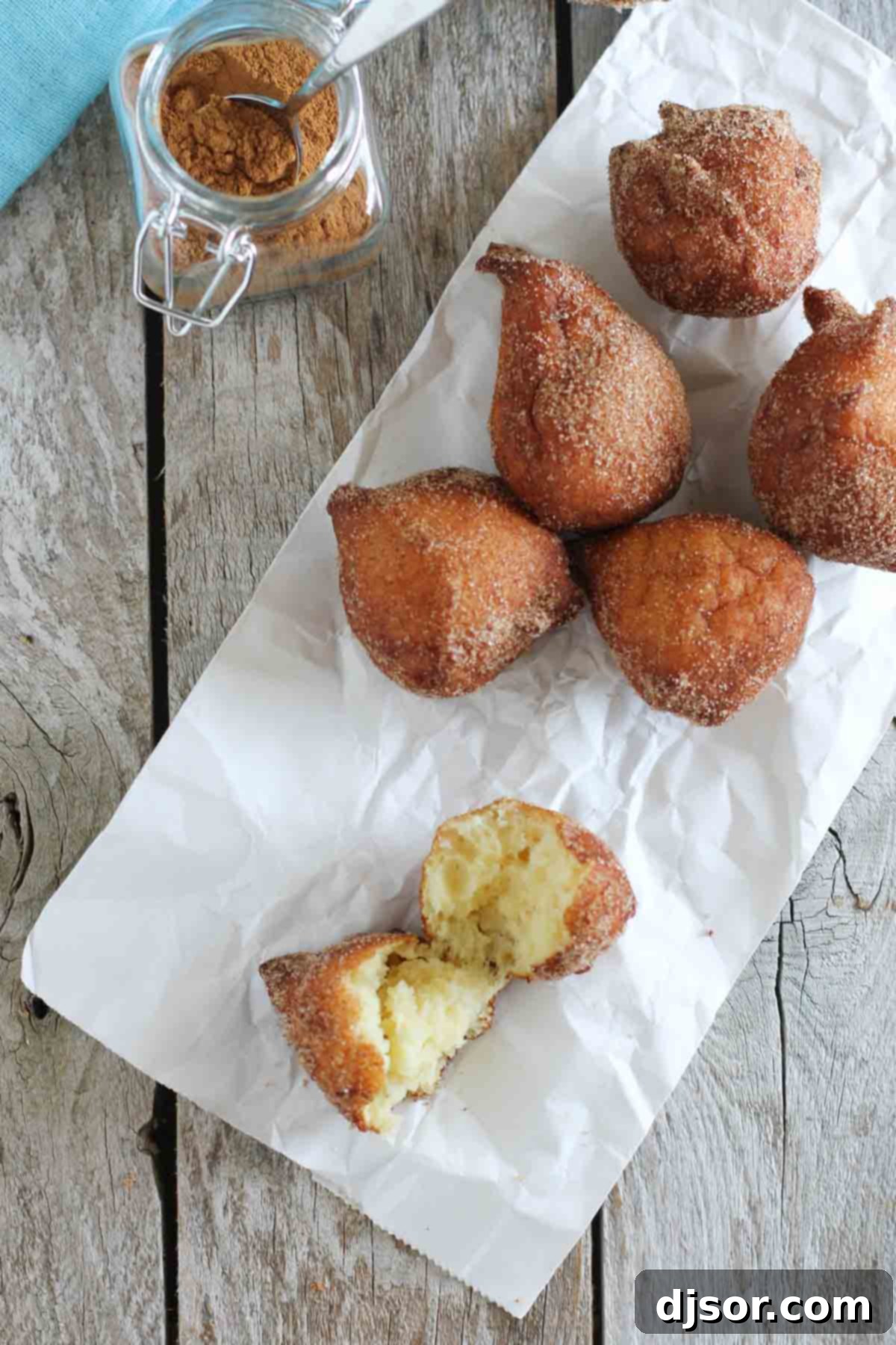 An array of cinnamon sugar ricotta doughnuts, with one perfectly torn in half to showcase its delicate, inviting interior.