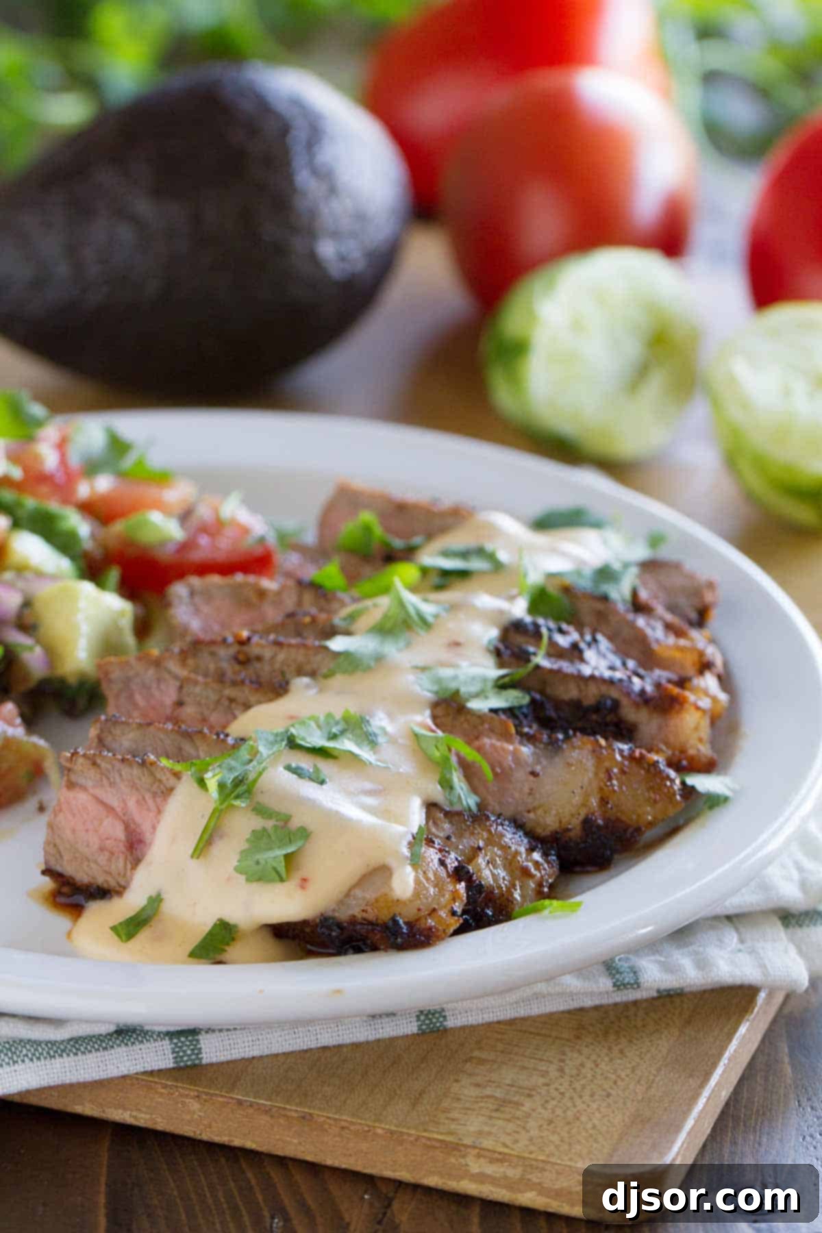 Zesty Mexican Steaks with Creamy Chile Queso 2 Plate with Mexican Spiced Steaks with Chile Con Queso, accompanied by a fresh tomato and avocado salad.