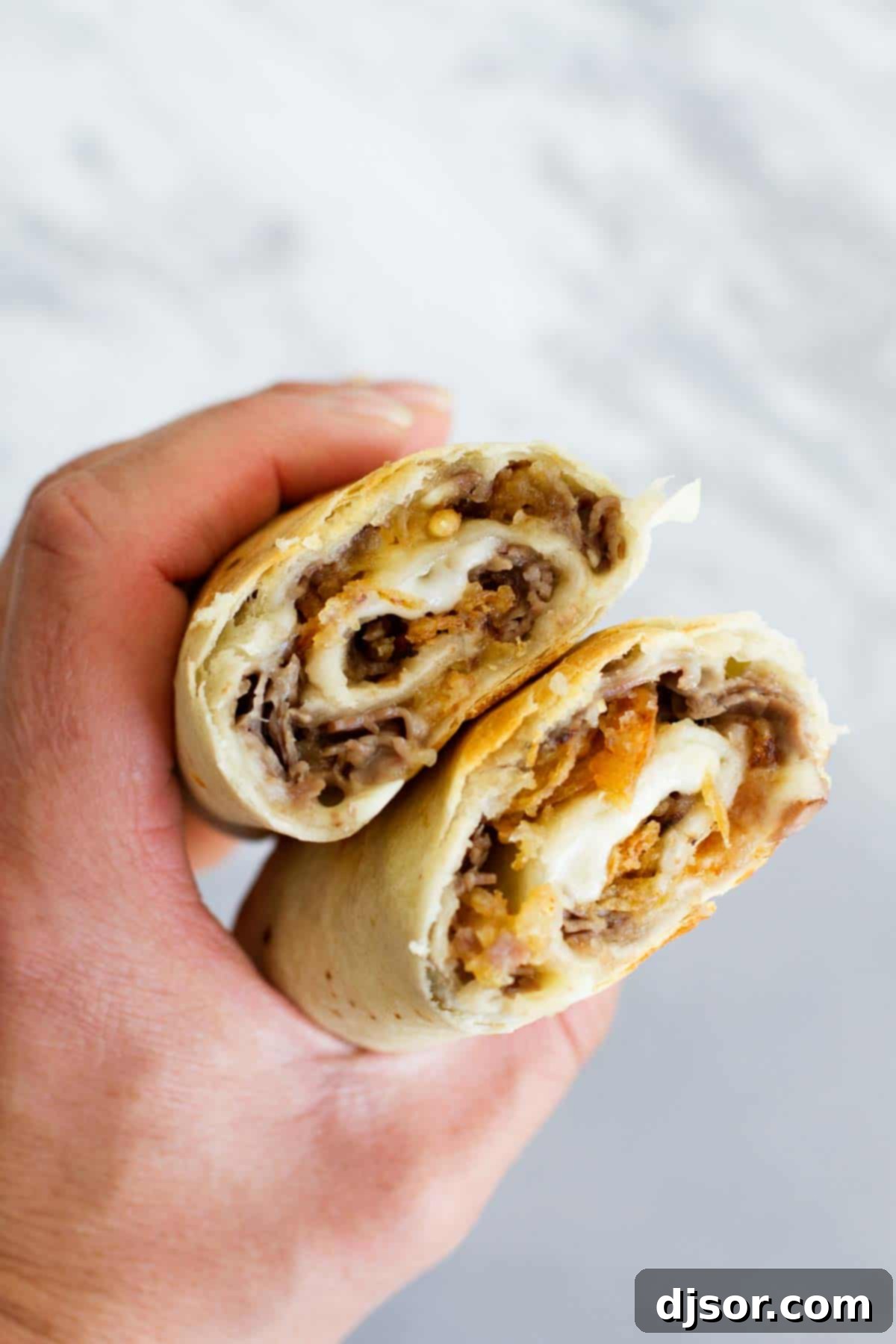 hand holidng French Dip Tortilla Roll Ups