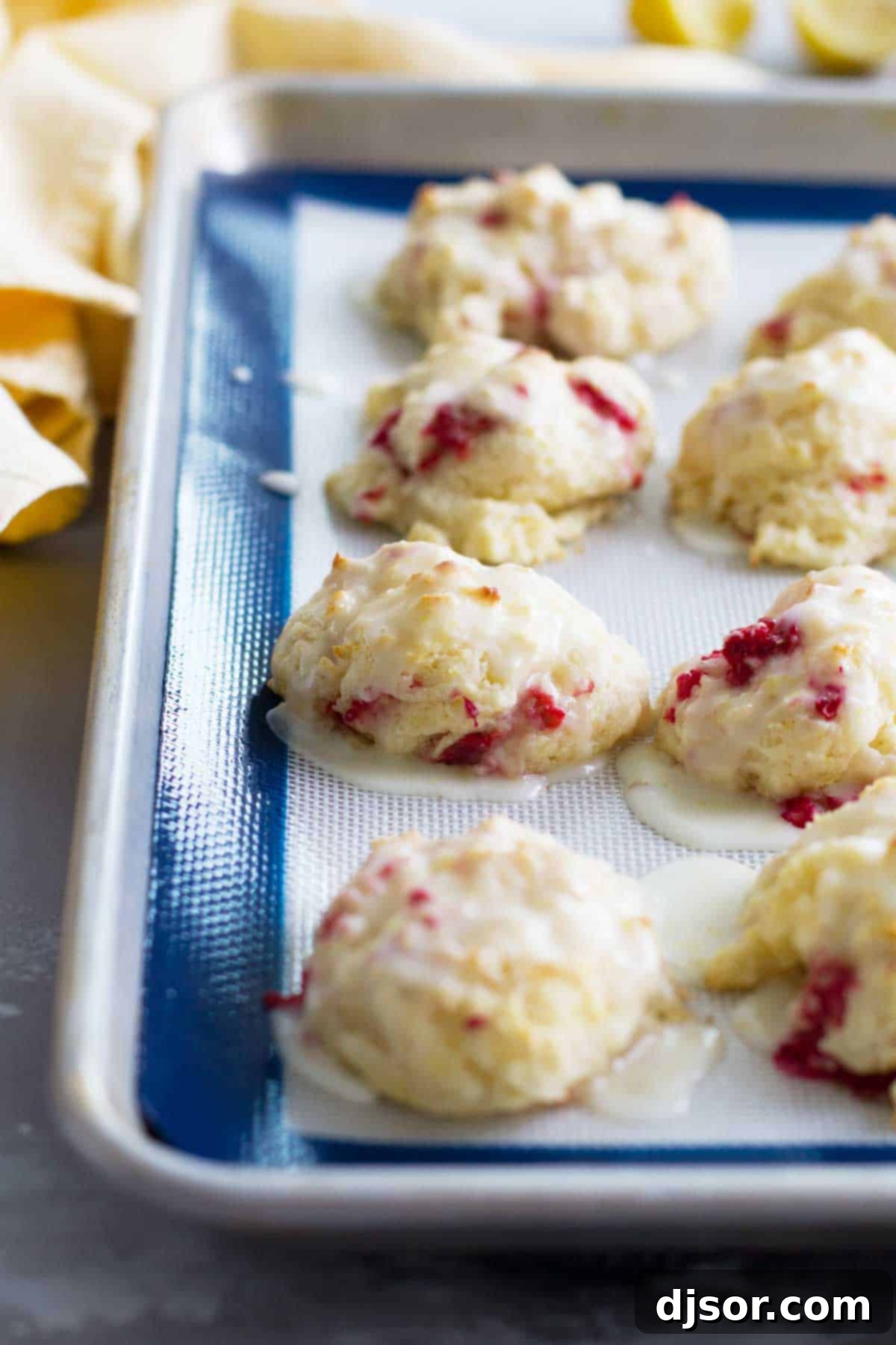 Moist and flavorful Raspberry Lemon Breakfast Biscuits with a bright lemon glaze. Delicious Raspberry Lemon Breakfast Biscuits fresh from the oven, drizzled with lemon glaze, on a white plate ready to be served for breakfast or brunch.
