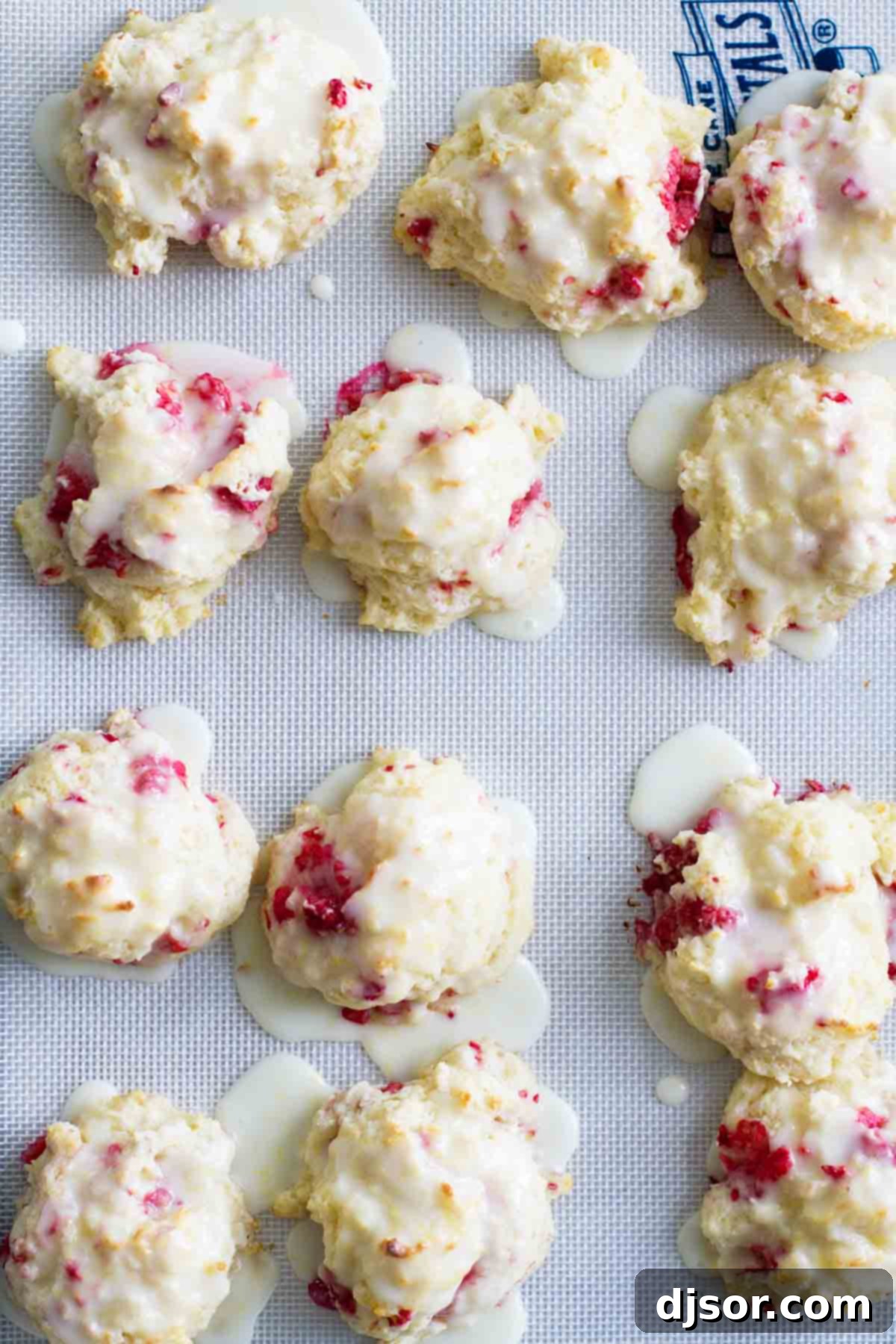 Golden-brown Raspberry Lemon Breakfast Biscuits on a baking sheet. Freshly baked Raspberry Lemon Breakfast Biscuits arranged on a parchment-lined baking sheet, golden brown and ready for glazing.
