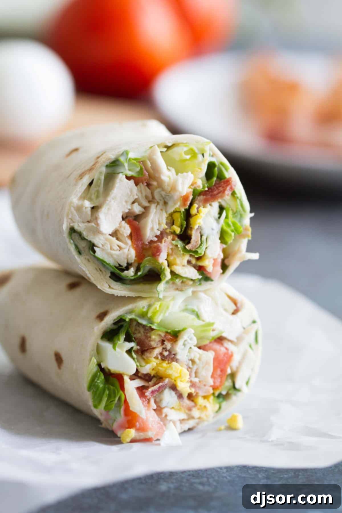 Two Chicken Cobb Salad Wraps, cut in half and stacked, showcasing the vibrant ingredients inside.