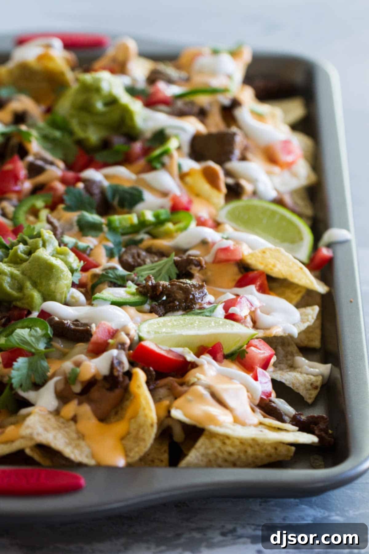 Close-up of Sheet Pan Nachos Supreme featuring rich steak and melted cheese.
