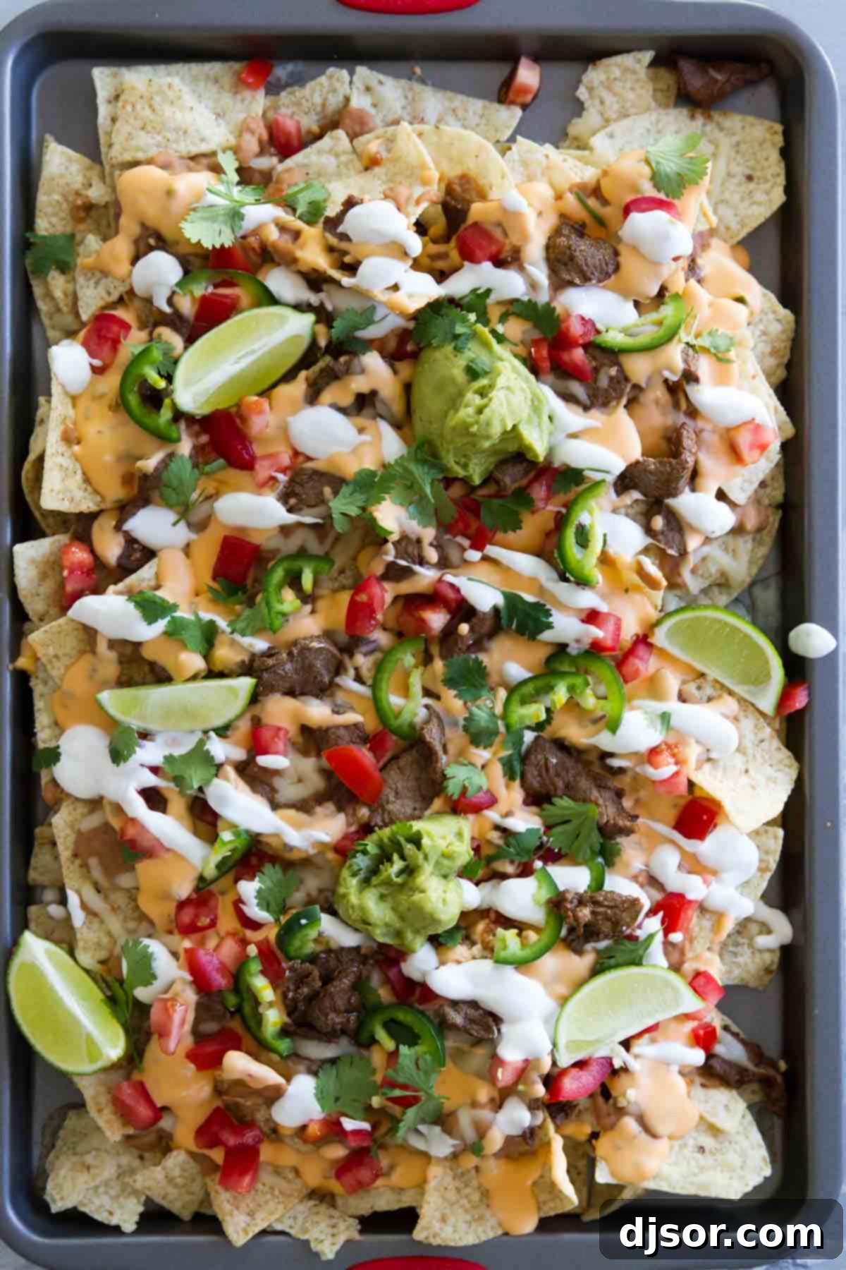 Fully loaded Sheet Pan Steak Nachos Supreme with a variety of colorful toppings.