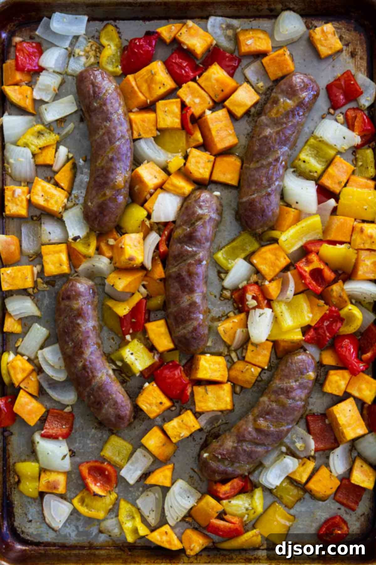 Sheet Pan Sausage and Peppers Recipe with Sweet Potatoes and onions - Close-up of roasted ingredients.
