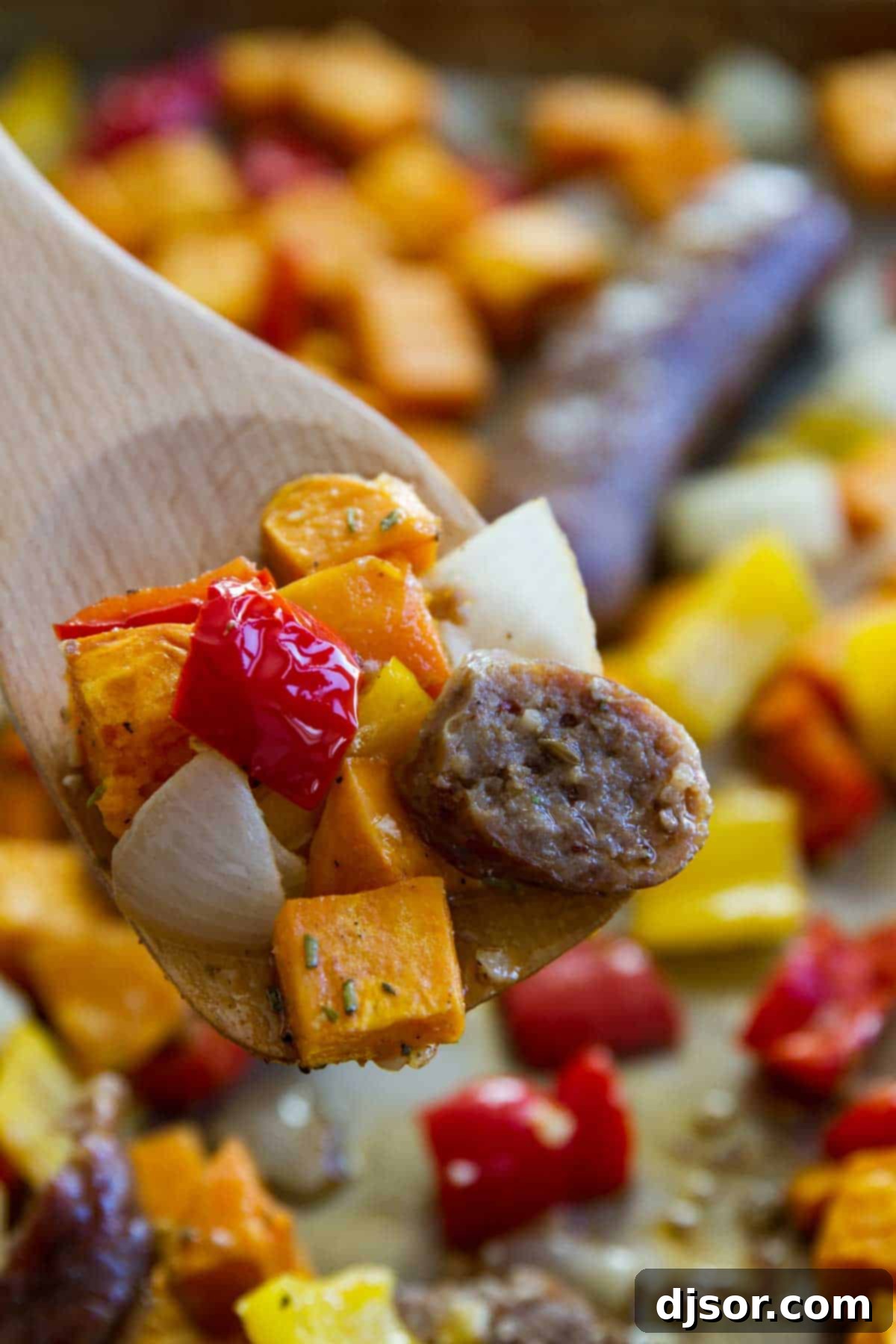 Easy Sheet Pan Dinner - Sausage and Peppers with Sweet potatoes on a wooden spoon - Ready to serve.