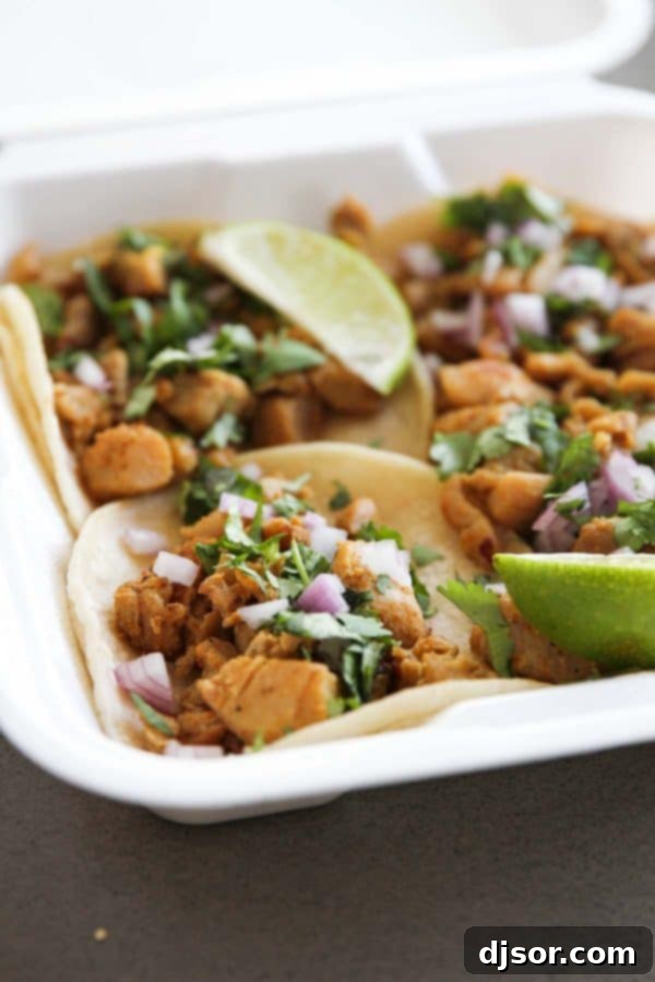 Three delicious chicken street tacos topped with cilantro and onions.