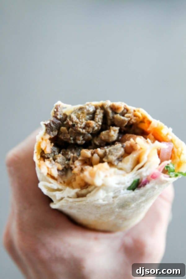 A generously filled carne asada burrito, showing the delicious filling inside.
